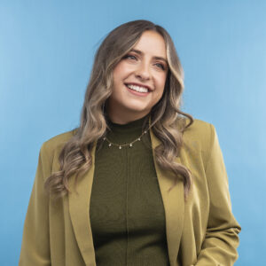 Portrait of Kate James, smiling just off-camera, in an olive-green blazer.